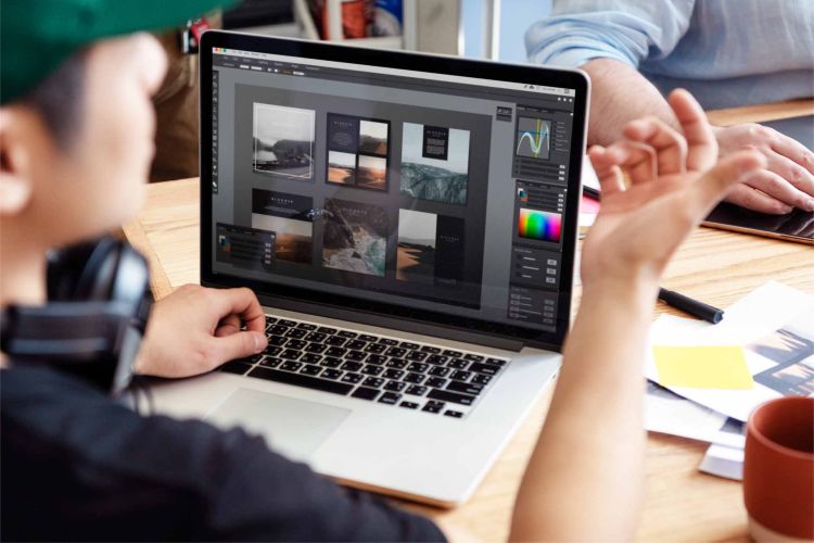 Grafik ze spójnia studio tworzy nowoczesny web design i układ wizualny dla nowej strony internetowej pracując na laptopie
